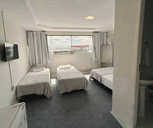 Quarto Triplo Solteiro com três camas de solteiro e janela ampla